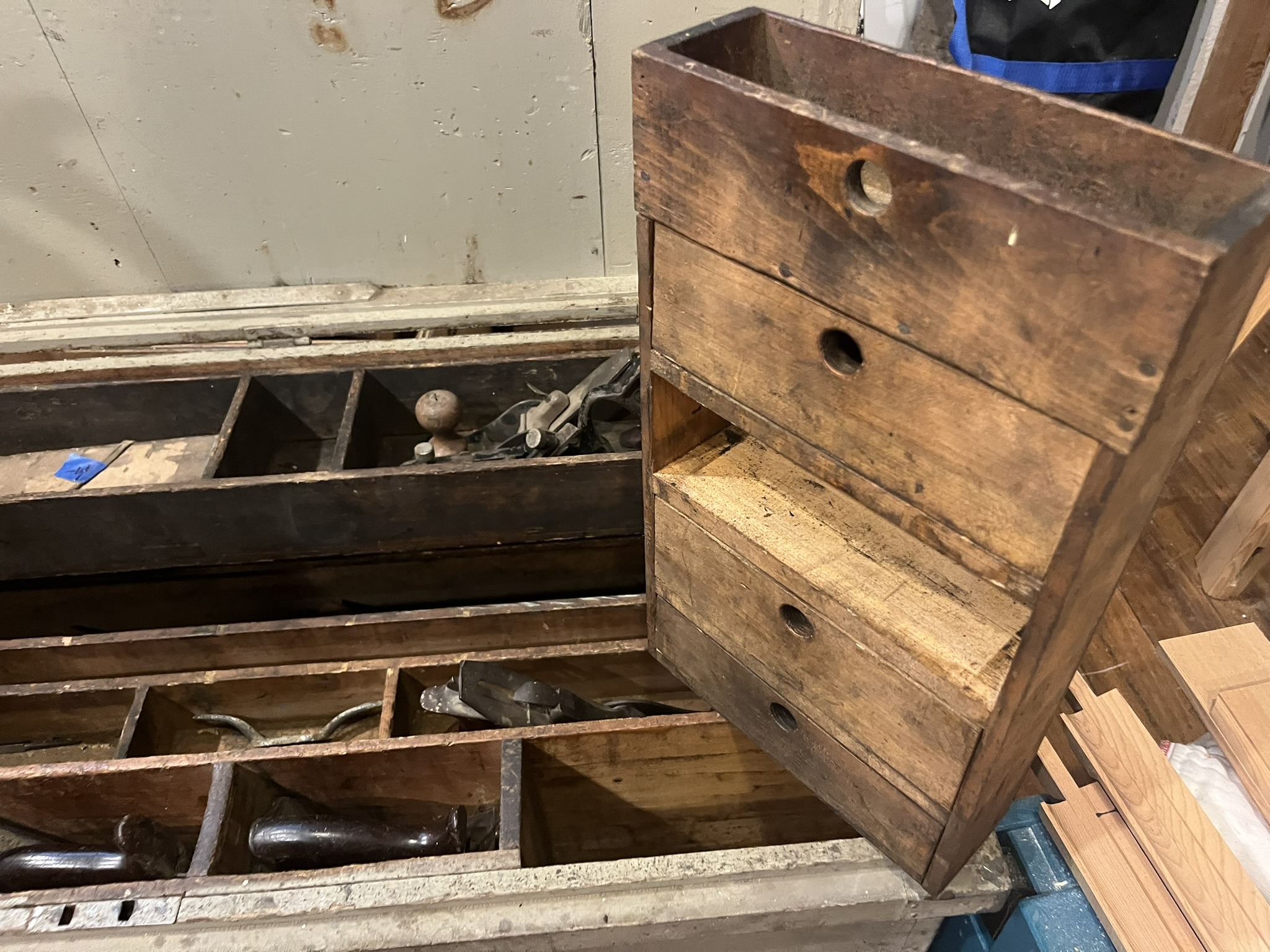 A lift-out till held up beside the chest, showing the divided cubbies underneath