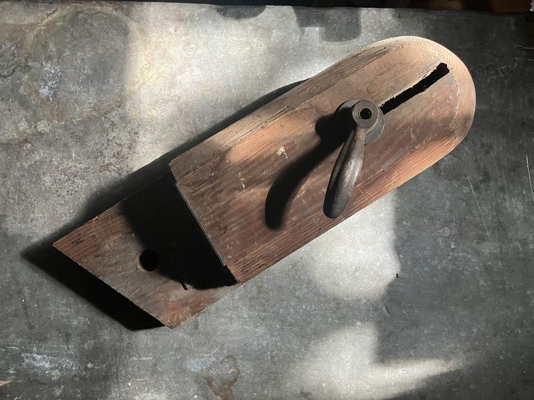 A wooden clamping vise with a rounded head and an iron lever