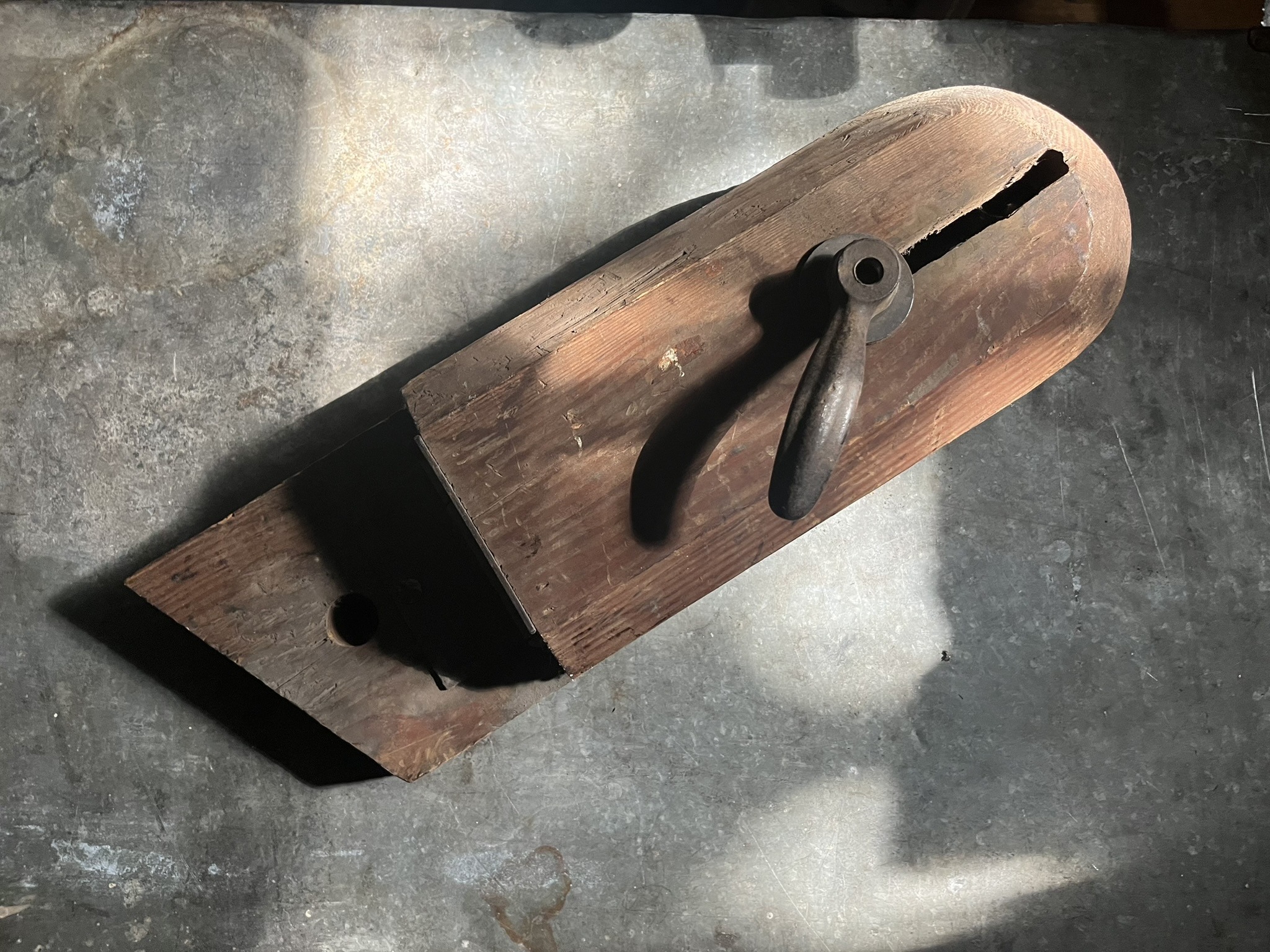 A wooden clamping vise with a rounded head and an iron lever