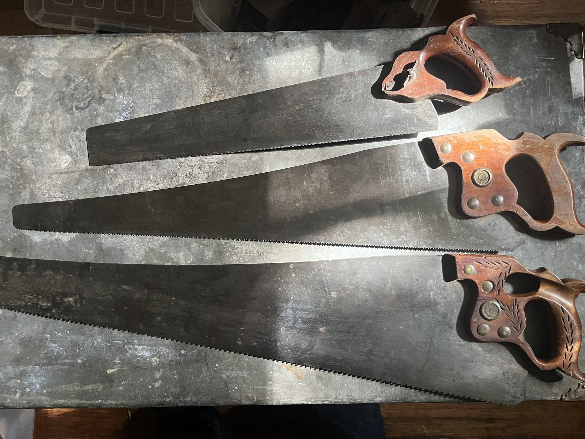 Three handsaws with carved applewood handles and etched blades